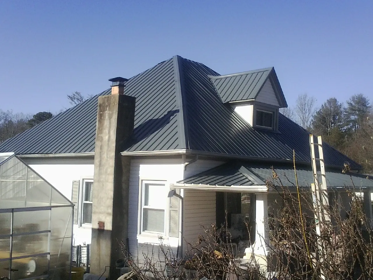 Dark blue standing seam metal roof on a white farmhouse with dormer — Slate & Tile Roof Repair by Roofing Brothers in Old Greenwich