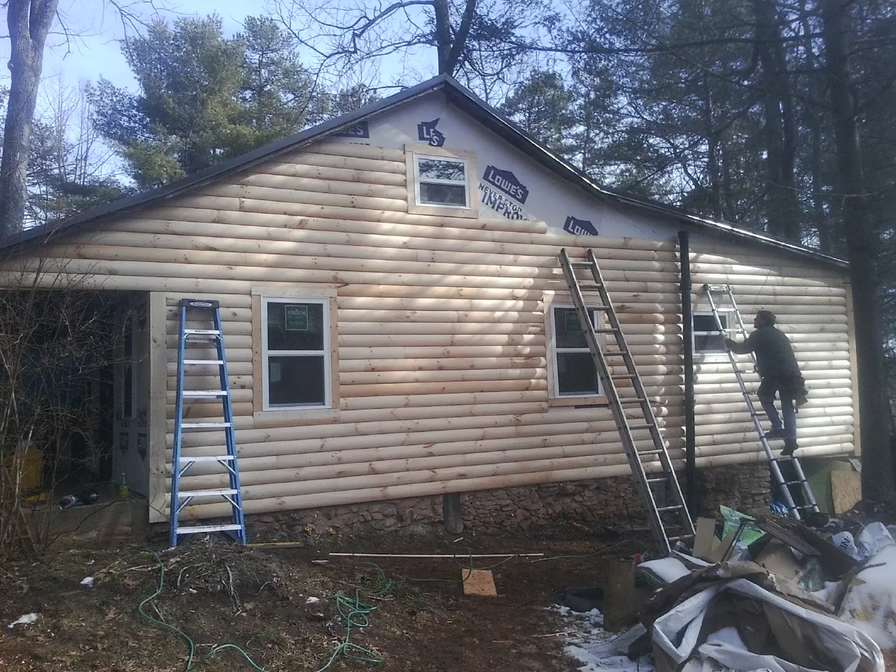 Ladders set against fresh log siding during an exterior remodel in Old Greenwich