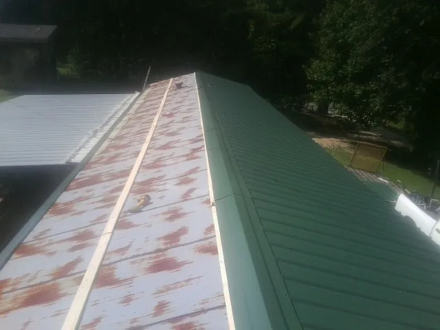 Old rusted panels beside newly installed green metal roofing — Wind Damage Roof Repair by Roofing Brothers in Old Greenwich