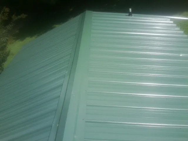 New green metal panels meeting at the ridge of a roof — Flat Roof Repair work by our crew in Old Greenwich