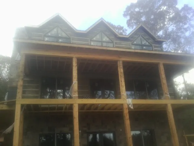 Dormers and porch framing on a large log home under construction — Roof Coating work by our crew in Old Greenwich