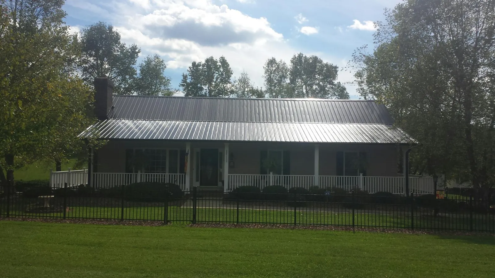 Gray metal roof on a brick ranch with a full width front porch — Gutter Guard Installation work by our crew in Old Greenwich