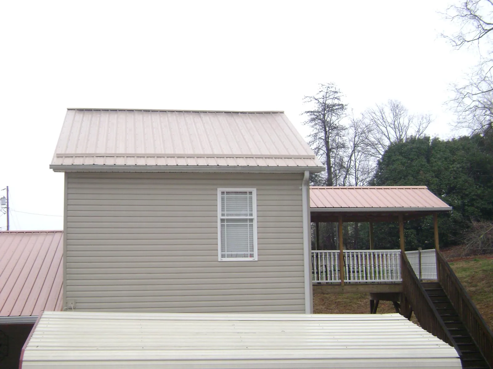 Tan metal roofs on a two story addition and attached porch, from a Roof Replacement job in Old Greenwich