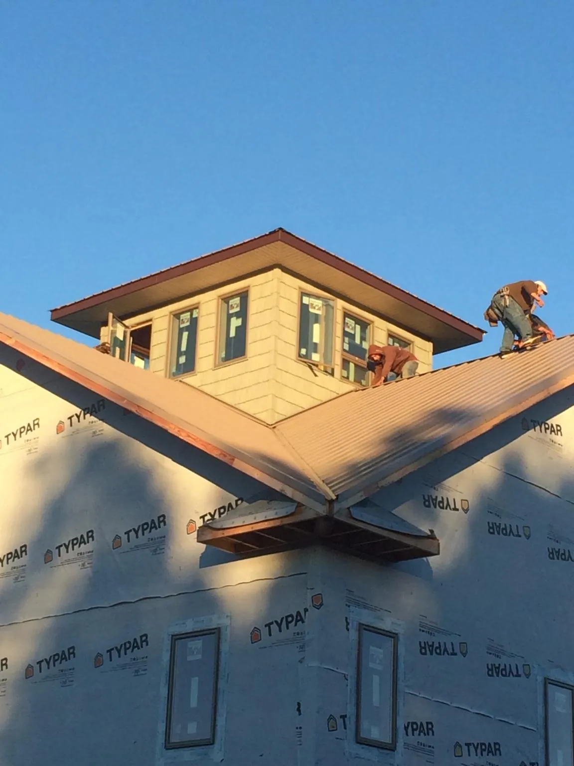Roofers working around a rooftop cupola on a new metal roof at sunset — Roof Waterproofing in Old Greenwich by Roofing Brothers
